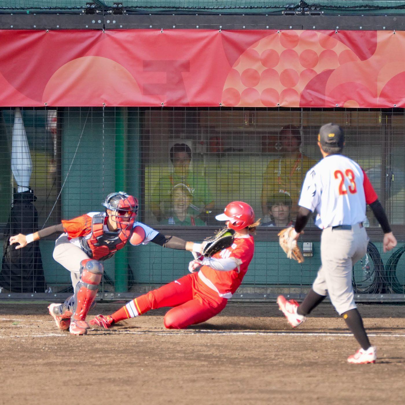 Una corredora de Japón se desliza en el plato ante la receptora china en la final. Foto: Ryoji Suzuki (@r.s.152).