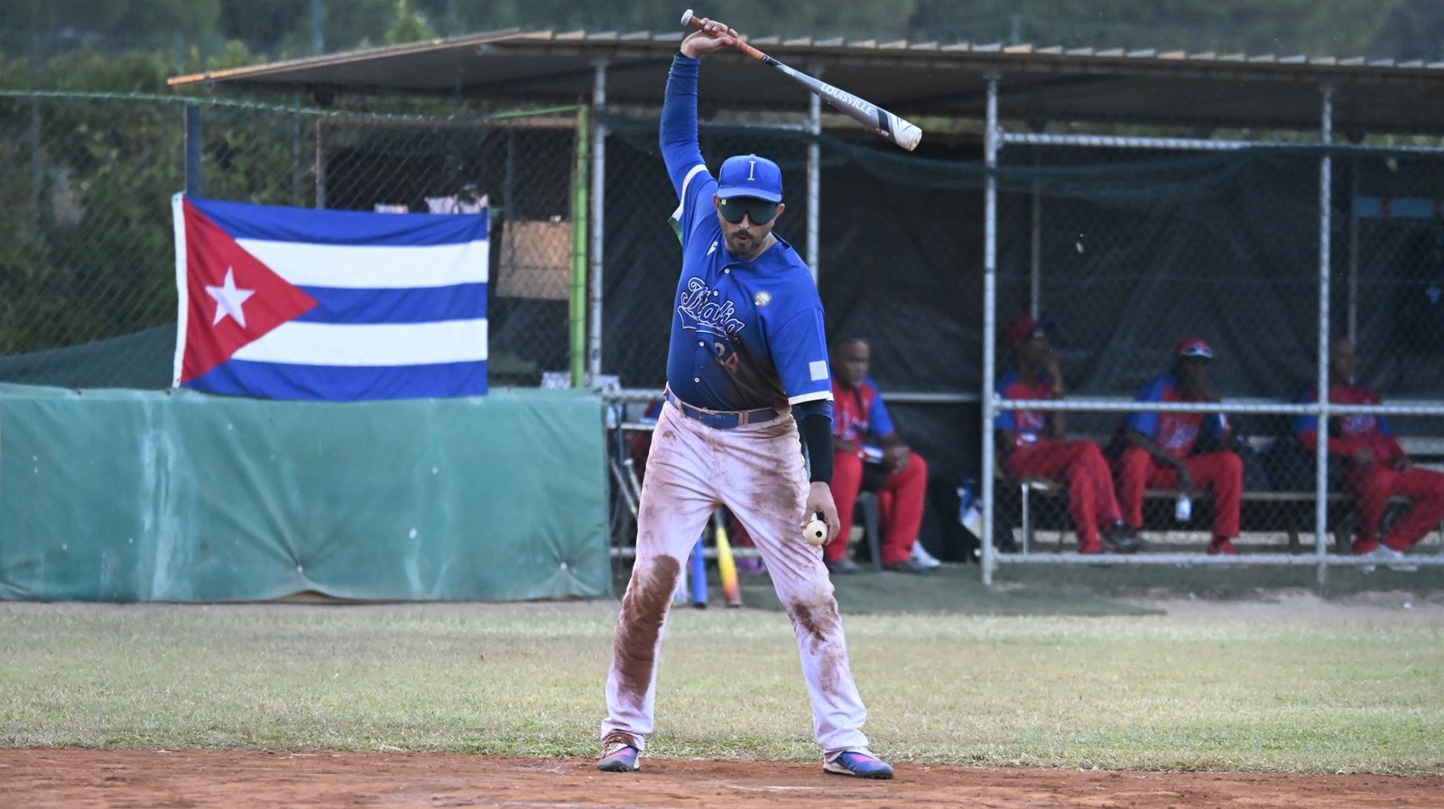 Un bateador de Italia (#28) se prepara en el plato ante el dugout de Cuba. Foto: WBSC.